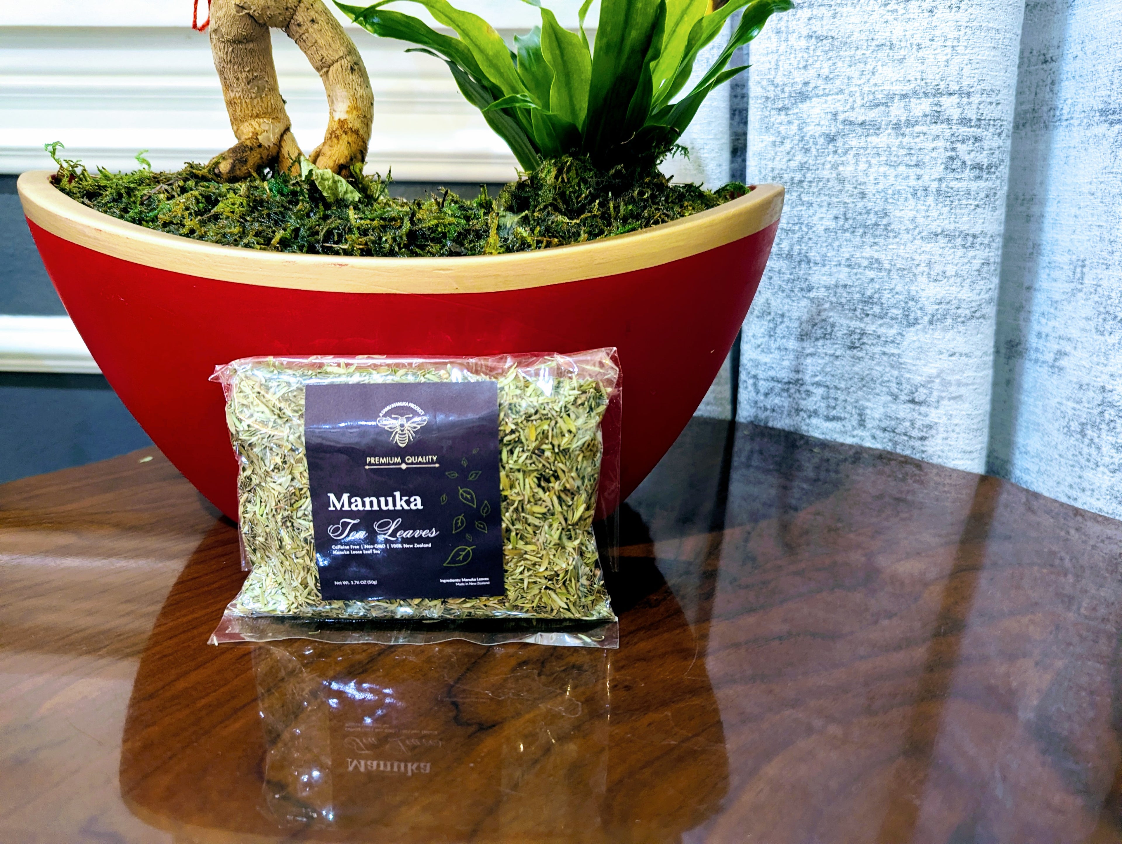 Manuka honey package on a wooden surface with plants in the background